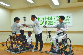 車いすフェンシングの加納慎太郎選手（右）と、笹島貴明選手（左）。真ん中で説明する小松理事長